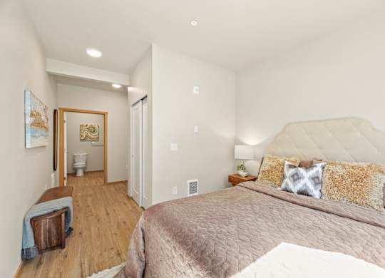A bedroom with a large bed and a wooden floor.