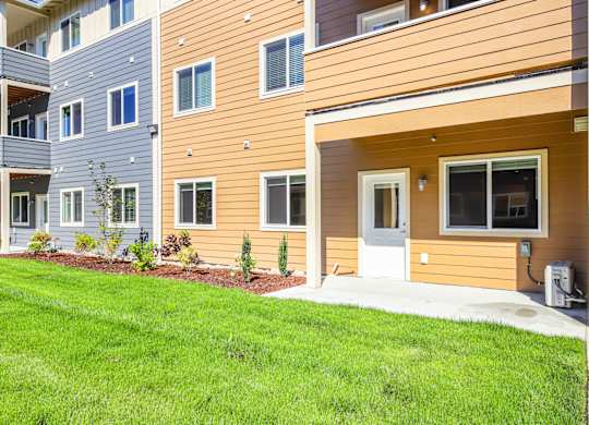 A modern apartment complex with a mix of grey, beige, and brown exterior colors.