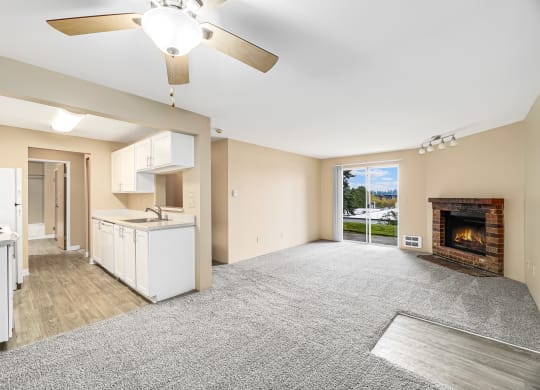 an empty living room with a fireplace and a kitchen