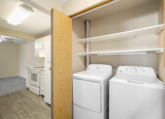 a white washer and dryer in a room with a door to a closet
