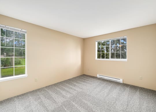 an empty room with two windows and carpeting