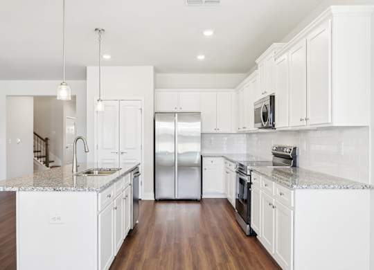 A modern kitchen with white cabinets and a granite countertop.
