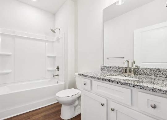 A white bathroom with a marble countertop and a white toilet.