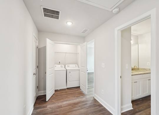 A white bathroom with a wooden floor and a white door.