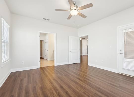 A room with a ceiling fan and wooden flooring.