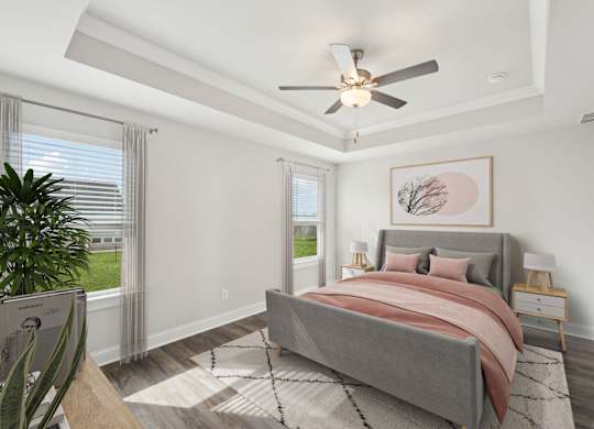 Primary bedroom with trayed ceiling and fan