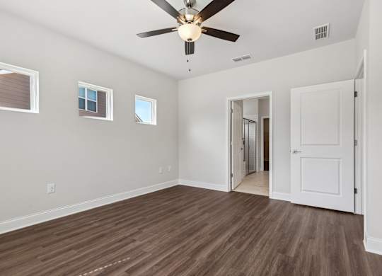 A room with a ceiling fan and wooden flooring.