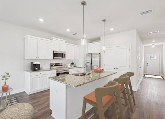 A modern kitchen showcasing a granite countertop island with bar seating and premium stainless steel appliances.