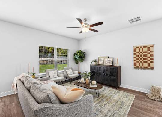 A living room with a grey couch, a coffee table, and a ceiling fan.