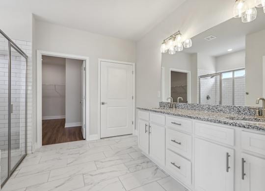 A bathroom with marble flooring and white cabinets.
