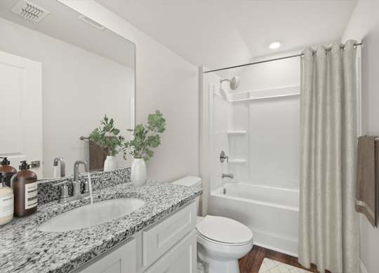 A white bathroom with a marble countertop and a white toilet.