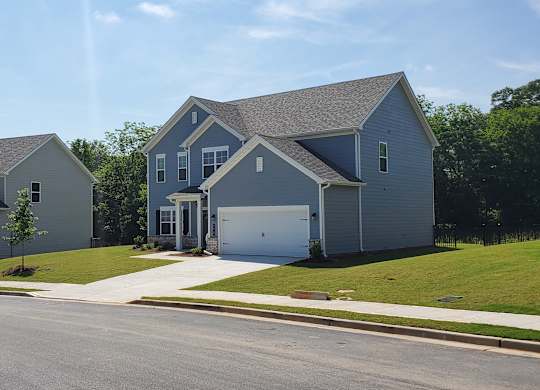 A row of houses with a driveway in front of them.