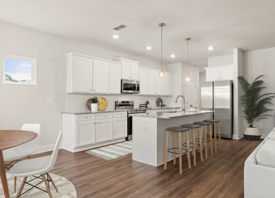 an open kitchen and living room with white cabinets and a bar with stools