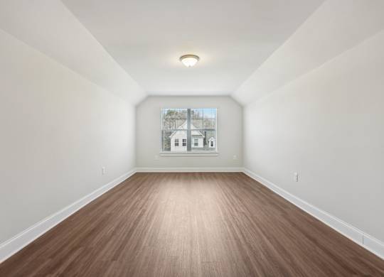 A room with wooden flooring and white walls.