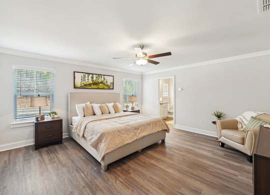 A bedroom with a bed, chair, and a painting on the wall.