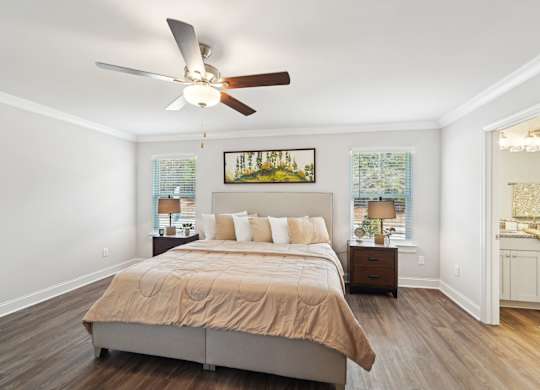 A bedroom with a bed, nightstand, and a painting on the wall.