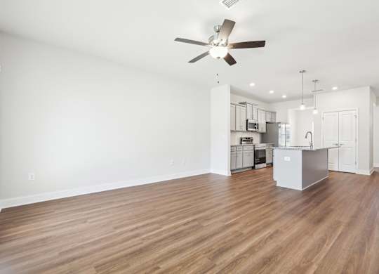 A room with a ceiling fan and wooden flooring.