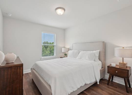 Secondary bedroom with a queen-size bed and bright natural light streaming through a large window.