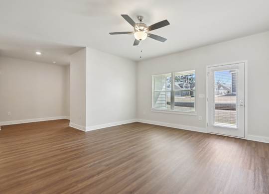 A room with a ceiling fan and a window overlooking a street.