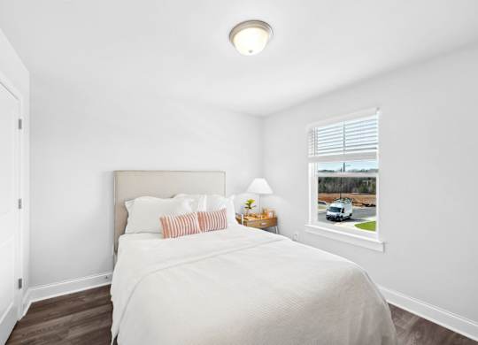 A bedroom with a bed, nightstand, and window.