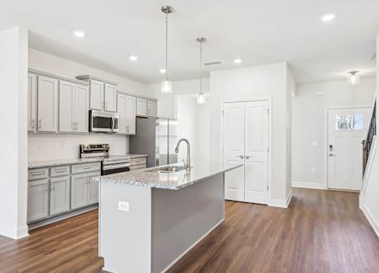 A modern kitchen with a central island and wooden floors.