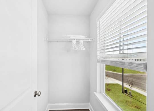 A white door with a white wall and a window with blinds.