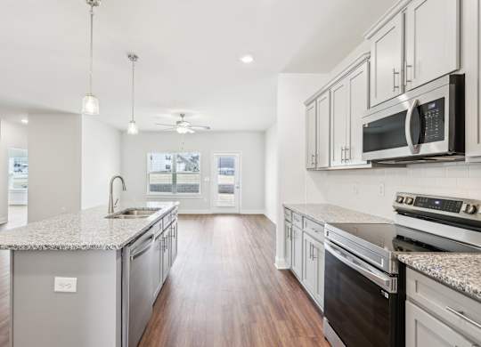 A modern kitchen with a granite countertop and stainless steel appliances.