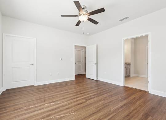 A room with a ceiling fan and wooden flooring.