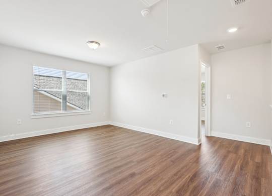 A room with wooden floors and a window with blinds.