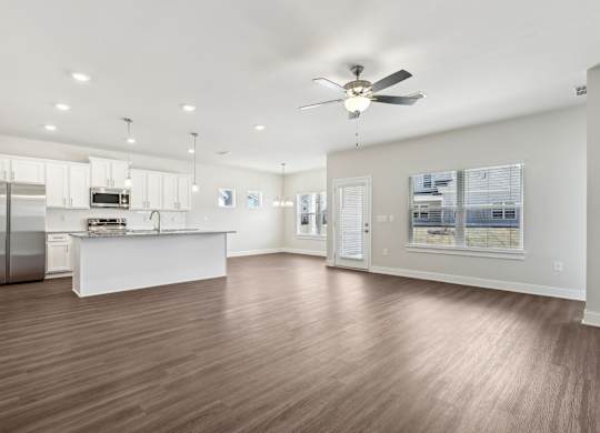 A spacious kitchen with a refrigerator, sink, and a ceiling fan.