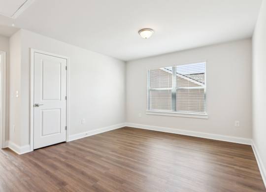 A room with a white door and a window with blinds.