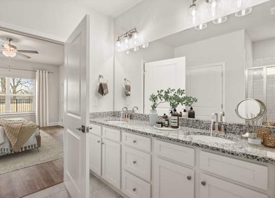 A bathroom with a large mirror, a sink, and a bedroom with a window.