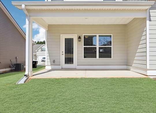 A house with a white door and windows with a green lawn in front.