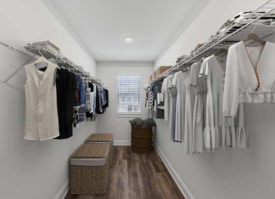 Primary suite with a full walk in closet featuring custom racks and a stylish bench.