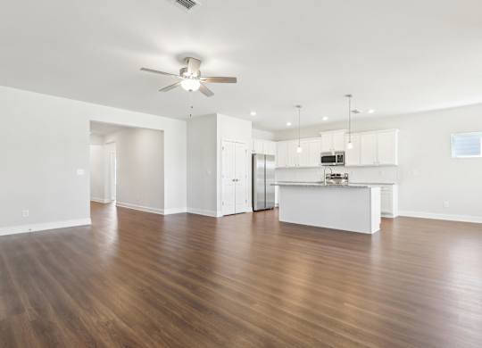 A spacious room with wooden floors and a ceiling fan.