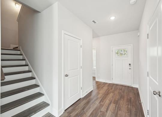 A hallway with white walls and wooden floors.