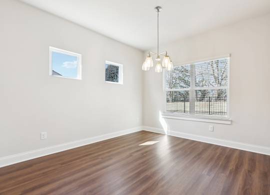 A room with wooden floors and a large window with a view of trees.