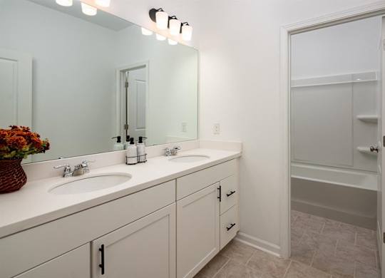 Alternate view of the third bathroom showcasing a double vanity and a tub-shower combination.