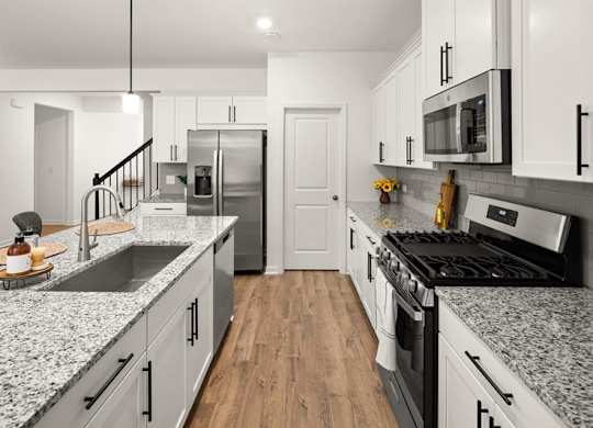 Spacious kitchen with an island, ample storage, stainless steel appliances and view into the living room.
