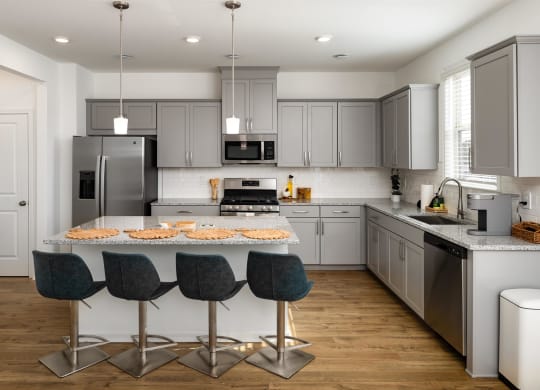 a kitchen with gray cabinets and an island with four chairs