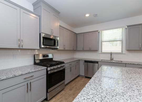 an empty kitchen with white cabinets and granite counter tops
