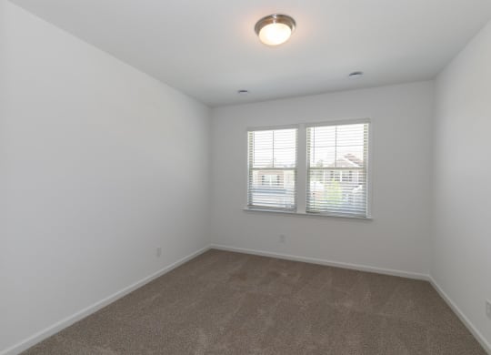an empty living room with carpet and a window