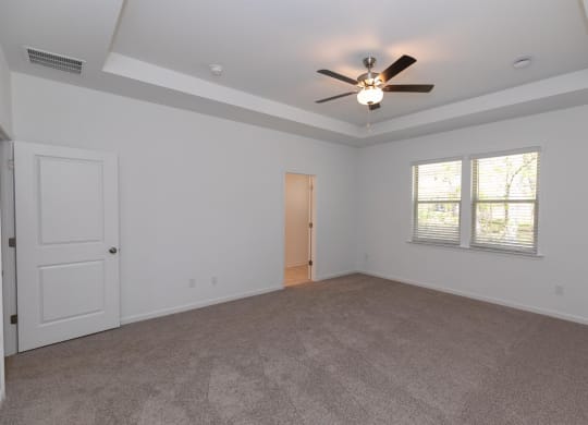 an empty living room with a ceiling fan and a window