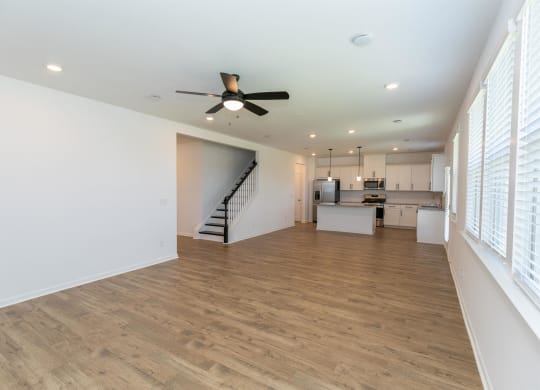 a living room with a ceiling fan and a kitchen