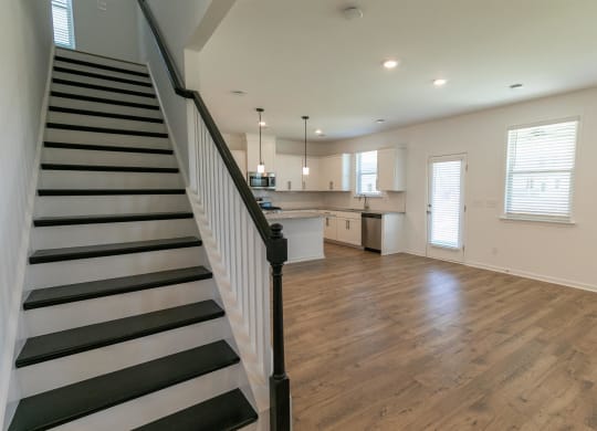 a view of a living room and staircase with a kitchen in the background
