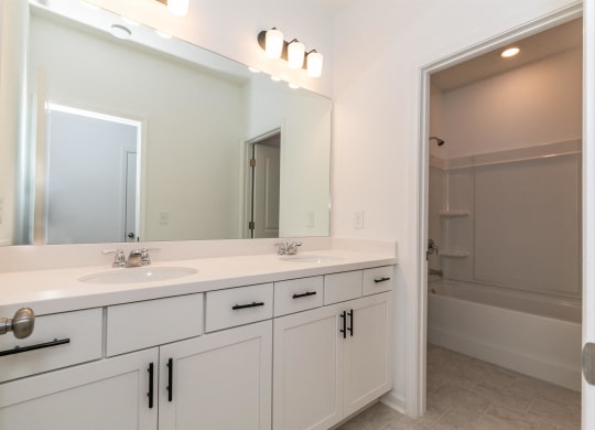 a white bathroom with two sinks and a mirror