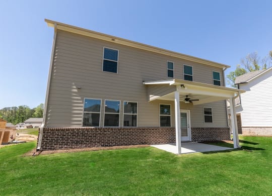 a tan house with a porch and a green lawn