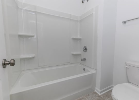 a white bathroom with a tub and a toilet