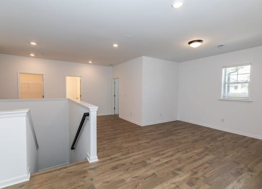 a newly renovated living room with white walls and wood flooring