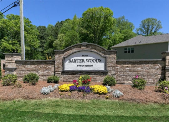 the exterior of theatter wood sign in front of a brick retaining wall with flowers